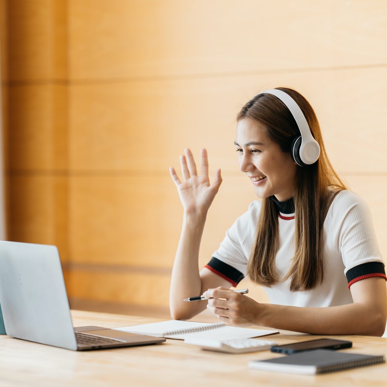 Smiling Asian young female using headset looking at laptop screen listen and learning online courses